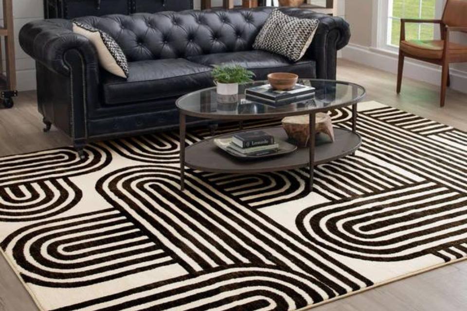 black and white patterned are rug in living room with leather couch and dark wood coffee table